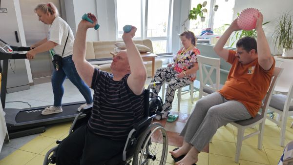 Osoby z niepełnosprawnościami ćwiczą z ciężarkami, piłkami i na bieżni.