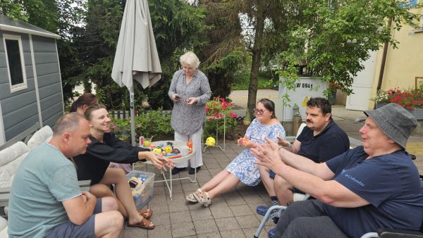 Osoby z niepełnosprawnościami siedzą na tarasie.